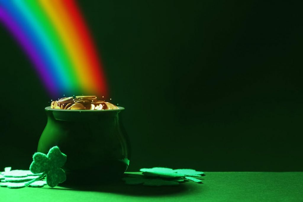 Pot with gold coins and clover leaves on green table, space for